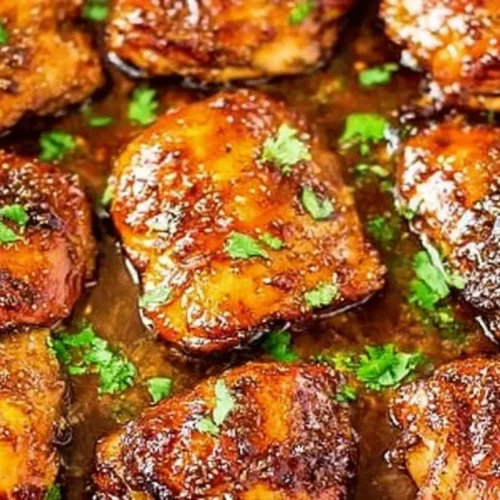 A plate of glossy brown sugar garlic chicken garnished with fresh parsley.