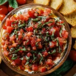 Colorful bruschetta dip served with toasted bread pieces as an appetizer.