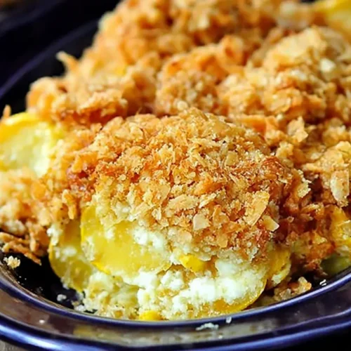 A golden-brown squash casserole with a crispy topping in a white baking dish.