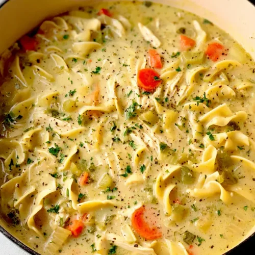 A steaming bowl of creamy chicken noodle soup garnished with fresh parsley