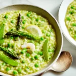 A bowl of fresh spring risotto garnished with green herbs and vegetables.