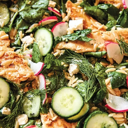 A close-up of a one-skillet chicken with buttery orzo dish, garnished with fresh herbs.