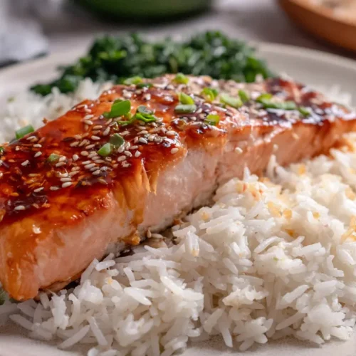 A perfectly cooked salmon fillet next to fluffy white rice.